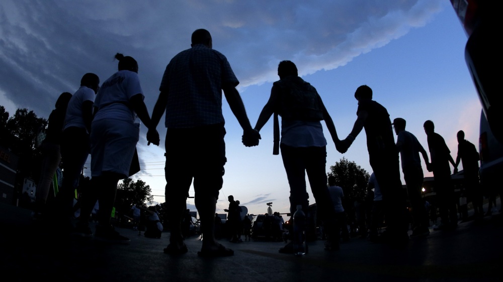 People stand in prayer after marching about a mile to the police station to protest the shooting of Michael Brown in Ferguson, Mo., in August.